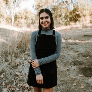 woman in gray long sleeve shirt and black skirt standing on brown dried leaves during daytime